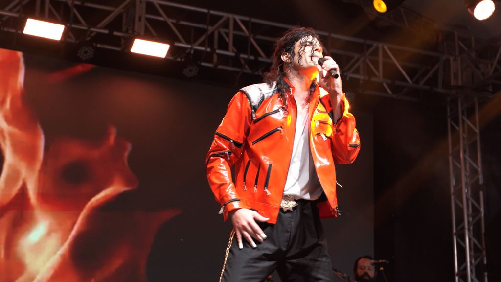 Michael James com jaqueta vermelha cantando no palco